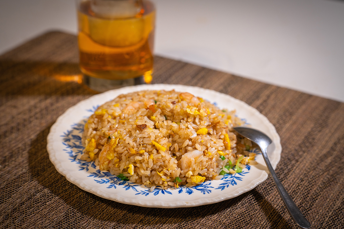 Fried rice with shrimp, egg, scallions, and vegetables served on a patterned plate