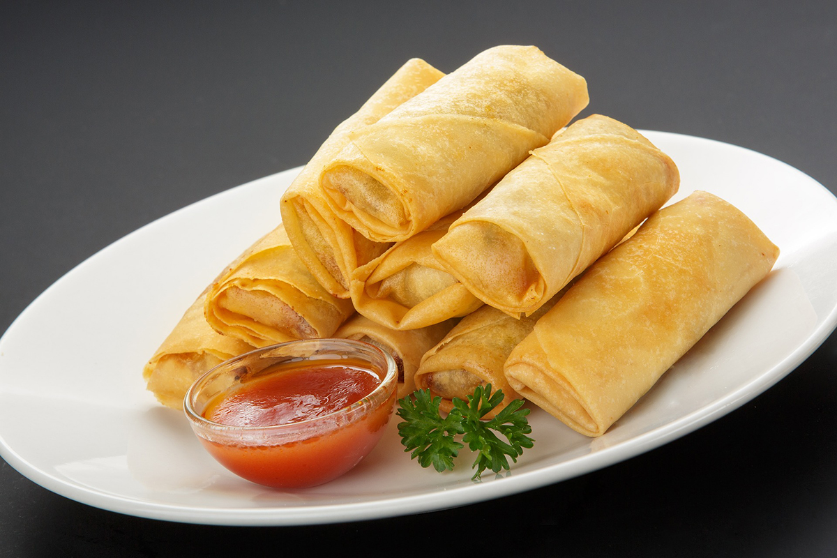 Golden crispy spring rolls served with sweet red dipping sauce