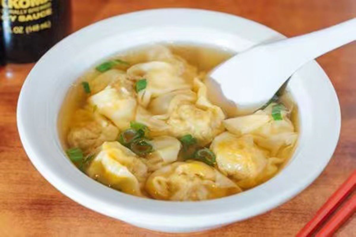 Wonton soup with tender dumplings and chopped scallions in a clear broth